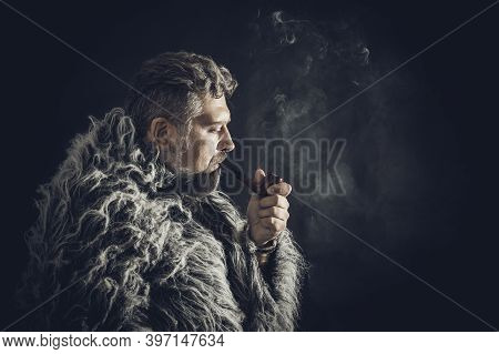 Solid Bearded Man In A Fur Mantle Smoking Pipe