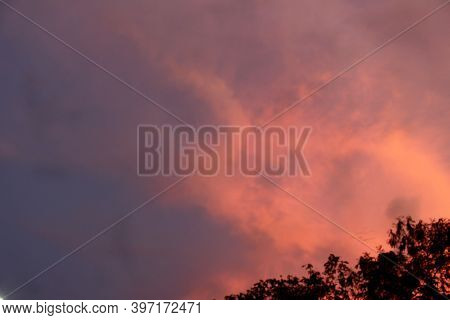 Evening Sky With A Mix Of Orange And Blue. There Is Also A Leaf Silhouette.