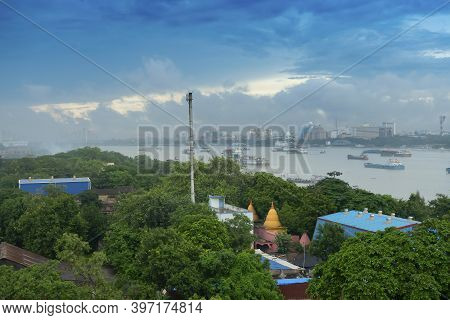 View Of Howrah City From Above. Green Trees In Foreground Covering Factories, Holy River Ganges With