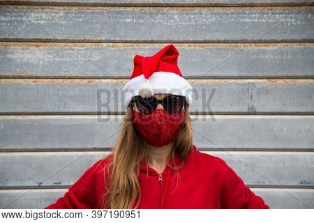 Caucasian Longhair Blond Girl In Black Sun Glasses, Red Protective Face Mask And Christmas Hat Portr