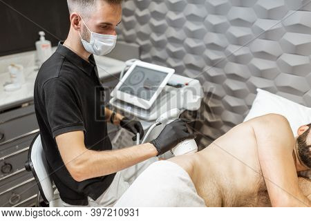 Man During An Ultrasound Liposuction Procedure At Luxury Spa Salon. Doctor Working On Waist Side Are