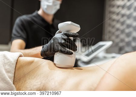 Man During An Ultrasound Liposuction Procedure At Luxury Spa Salon. Doctor Working On Waist Side Are
