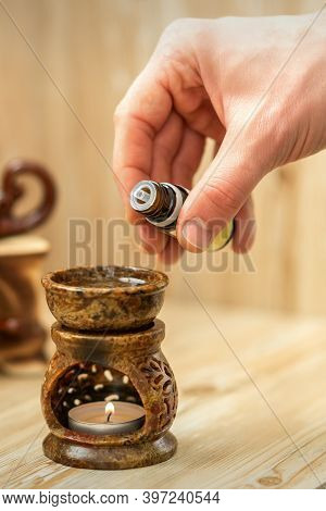 Hand Of Therapist Pours Drops Of Essential Oil To Ceramic Diffuser In Spa Salon