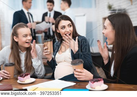 Two Young Girls Are Laughing At Work Annoying Boss. Two Women Are Standing In The Office With Papers