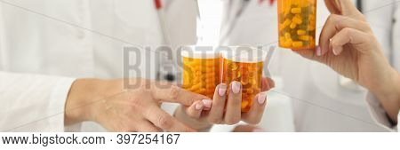 Doctors With Red Ribbon On Uniforms Are Holding Jars Of Medicines Closeup. Immunotherapy For Hiv Pos