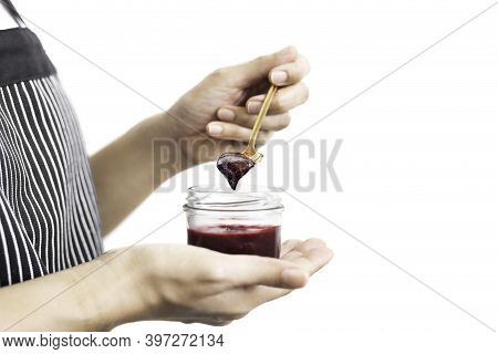 Woman Hand Holding A Spoon With Berry Jam In Jar In Clipping Path.