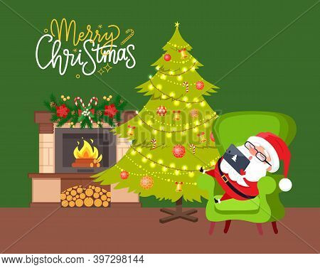 Santa Sitting On Green Armchair With Tablet Near Fireplace Decorated By Hanging Toys, Holiday Spruce