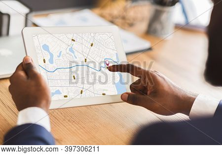 Unrecognizable Black Businessman Using Taxi Services App On Digital Tablet In Office, Looking At Vir
