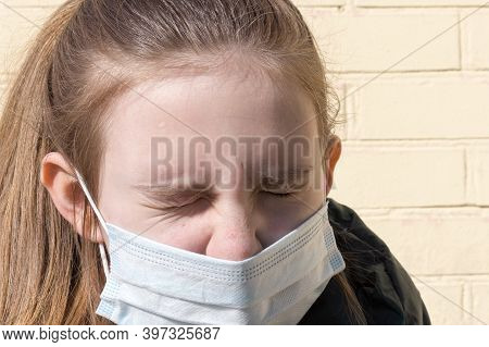 A Teenage Girl In A Medical Mask Sneezes