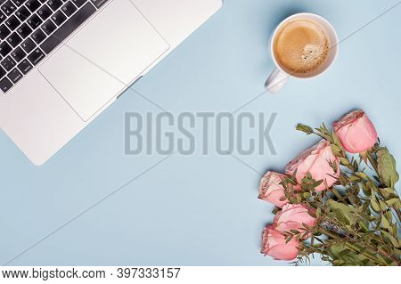 Flay Lay Cup Of Black Coffee, Laptop And Roses On Blue Paper Background