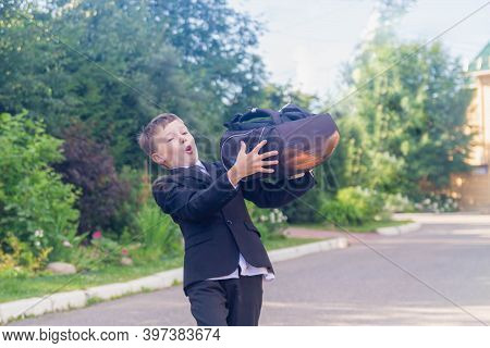 A Teenage Boy Is A European Schoolboy In A Black Suit, White Shirt. The Student Takes Off His Backpa