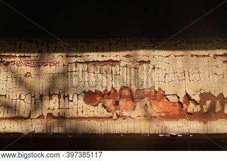 Cracked Paint On A Wooden Board In The Bright Sun. Shadows From Tree Leaves On The Texture Of Brown 