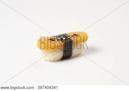 Sushi Nigiri Tomago. Japanese Omelet With Boiled Rice, Nori, Sesame Seeds And Teriyaki Sauce On A Wh