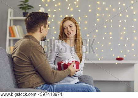 Young Smiling Woman Girlfiend Sitting And Getting Present Box With Ribbon From Loving Man
