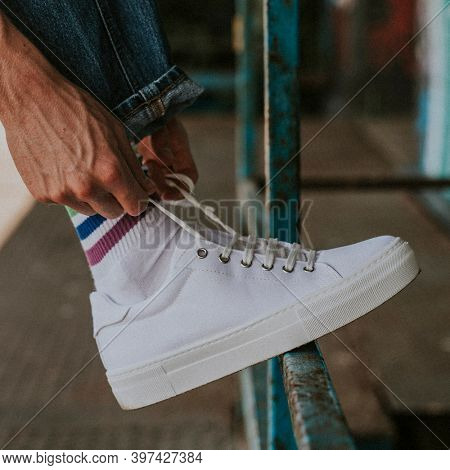 Man tying laces on a white sneaker