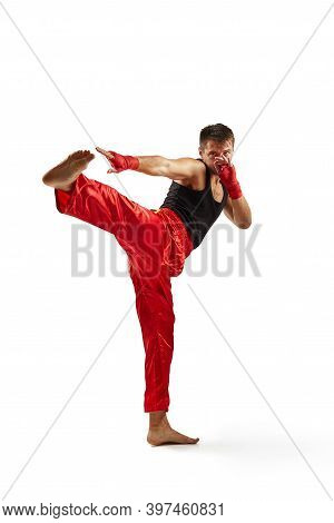 Athletic Man In Red Sports Bandages On His Hands Making Kick During Boxing Exercise, Isolated On Whi
