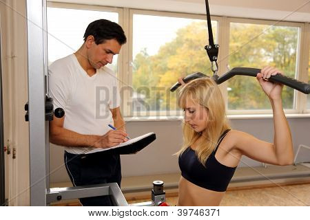 attraktive blonde Frau und ihr Trainer in einem Fitnessstudio