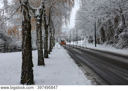 Snow Plow Is Sprincling Salt Or De-icing Chemicals On Pavement In City
