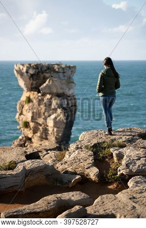 Woman In Sea Cliffs Landscape In Cabo Carvoeiro Cape Looking At Berlengas Island, In Peniche, Portug