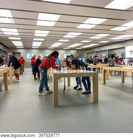 Salespeople And Customers At An Apple Store Looking At The Latest Apple Products For Sale.