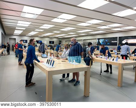 Salespeople And Customers At An Apple Store Looking At The Latest Apple Products For Sale.