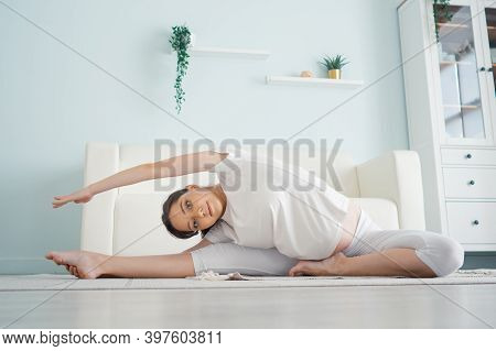 Beautiful Pregnant Woman Exercising While Sitting In Lotus Position. Pre-natal Exercises.