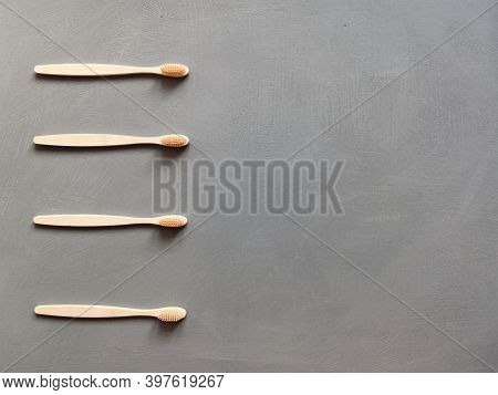 A Family Set Of Four Wooden Toothbrushes On Grey Background With Copy Space