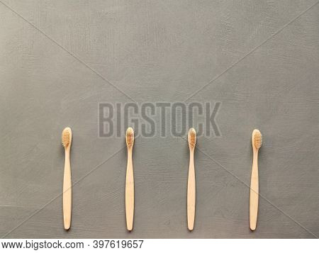 A Family Set Of Four Wooden Toothbrushes On Grey Background With Copy Space