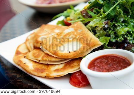 Delicious Mexican quesallidas made with chicken, tomato pieces and served with guacamole sauce.