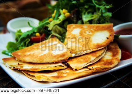 Delicious Mexican quesallidas made with chicken, tomato pieces and served with guacamole sauce.