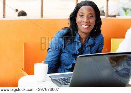 This Beautiful Young Woman Sitting At Her Laptop With A Cup Of Coffee In Front Of Her , Smiling At T