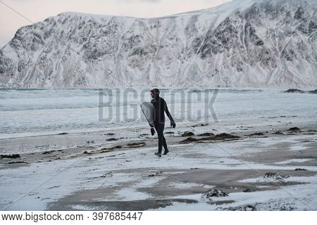 Arctic surfer going by beach after surfing