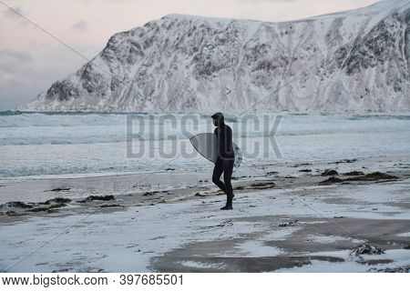 Arctic surfer going by beach after surfing