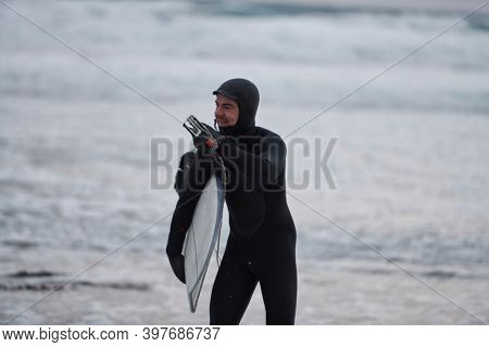 Arctic surfer going by beach after surfing
