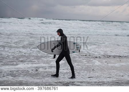 Arctic surfer going by beach after surfing