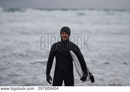 Arctic surfer going by beach after surfing