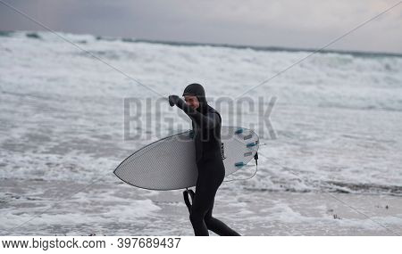Arctic surfer going by beach after surfing