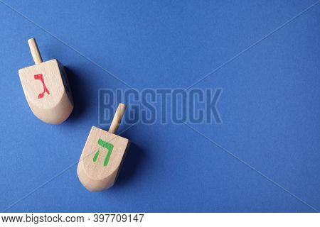 Hanukkah Traditional Dreidels With Letters Gimel And He On Blue Background, Flat Lay. Space For Text