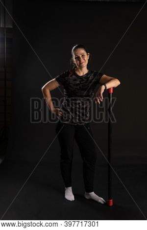 Fitness Rests On A Bodybar Holding Equipment. Goes In For Sports On A Black Background Looks At The 