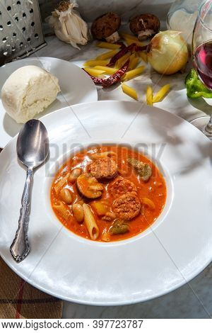 Creamy Italian Sausage Soup With Mozzarella Cheese Onions And Peppers Served With A Glass Of Red Win