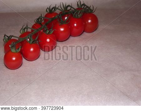 Cherry Tomatoes On Branches Close Up On A Beige Background. High Quality Photo