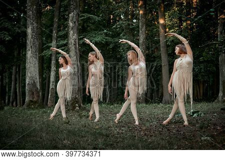 Four Young Female Dancers Dance Synchronously In The Forest Barefoot.