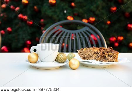 Coffee Pair Close With Golden Christmas Balls And A Piece Of Caramel Cake With Nuts. White Table, Gr