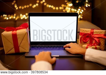 Detail Of Woman's Hand Working On Computer With Blank White Screen On Table With Gifts Blurred Chris