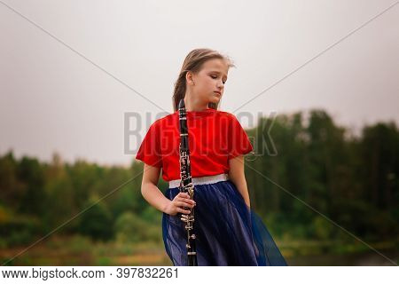 Young Attractive Girl Playing Clarinet, Ebony In Fall Park