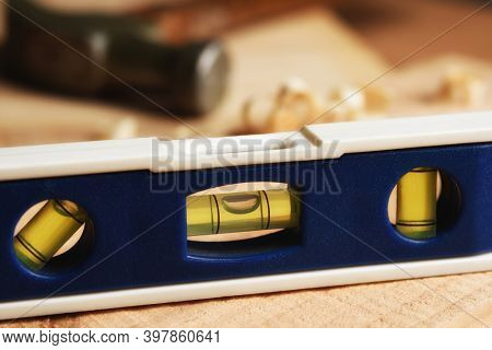 Closeup of a level on a woodworkers workbench with toold and wood shaving in the background.