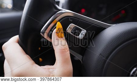 Woman Pressing Buttons On Steering Wheel. Action. Close-up Of Woman With Manicure Pressing Steering 