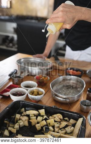 Divserse group of chefs in kitchen. trainee chefs standing at a table, preparing vegetable with seasonings.