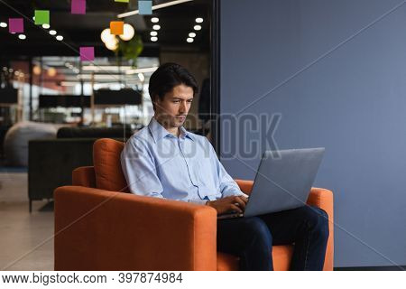 Caucasian businessman using laptop computer in creative office. social distancing in business office workplace during covid 19 coronavirus pandemic.