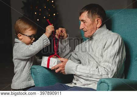 Elderly Grandfather And His Little Grandson Give And Open A Chri